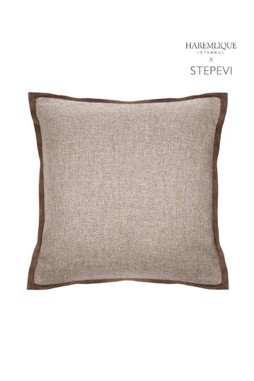 Primer plano de un cojín tejido marrón con ribete de terciopelo; con la marca HAREMLIQUE ISTANBUL X STEPEVI.